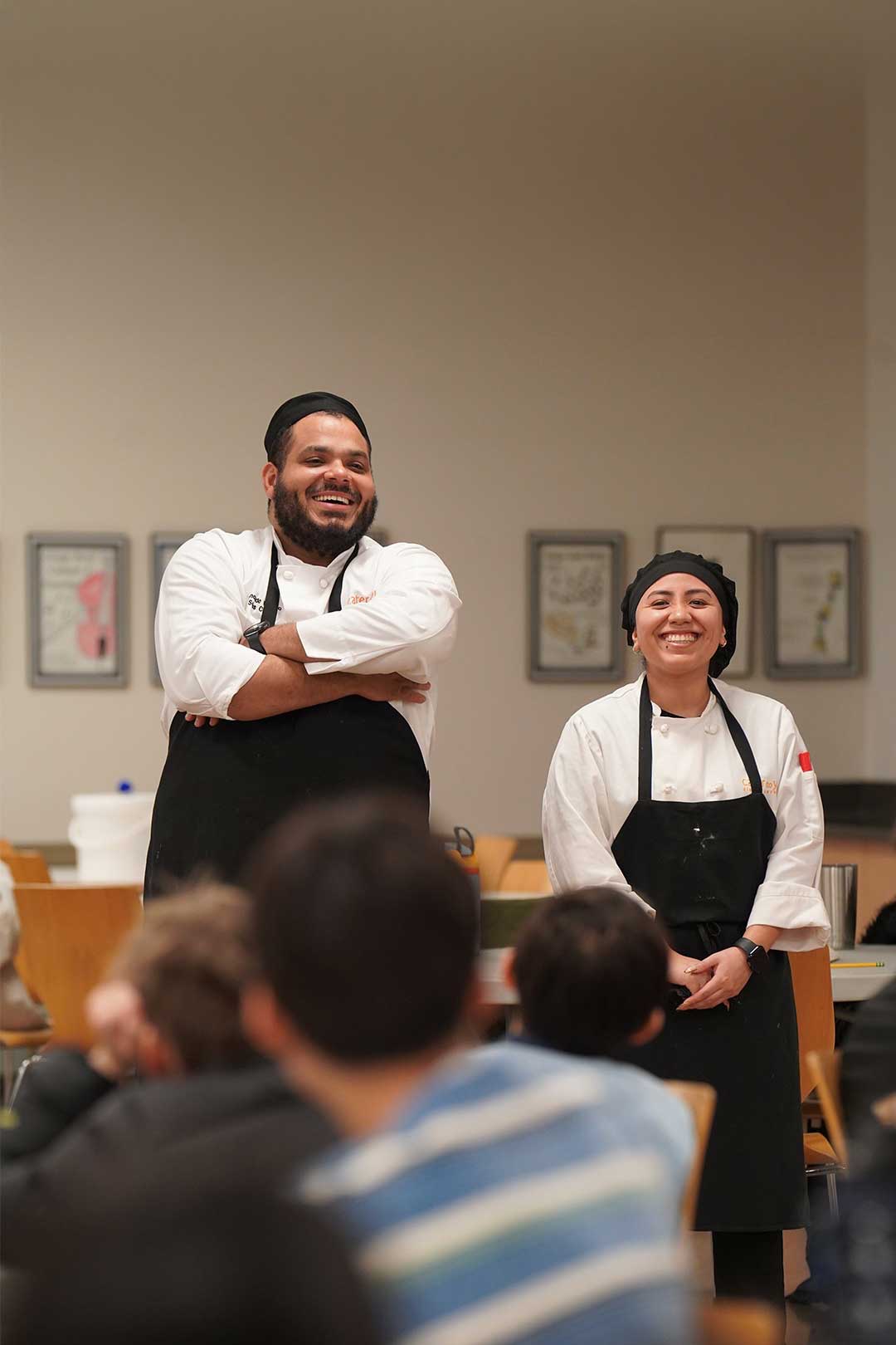 Staff smiling while standing in front of students in dining hall